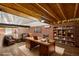 Bonus room is virtually staged as a home office with custom desk, bookshelves, brick wall, and exposed beam ceiling at 31 Twig Ct, Port Charlotte, FL 33954