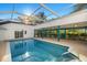 Beautiful in-ground pool with screened enclosure, covered seating area, and lush landscaping at 31 Twig Ct, Port Charlotte, FL 33954