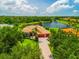 Stunning aerial view of home overlooking a lake with a large driveway, lush landscaping, and barrel tile roof at 312 148Th Ne Ct, Bradenton, FL 34212