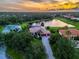 Panoramic aerial view of a lakefront property with lush landscaping and a barrel tile roof at sunset at 312 148Th Ne Ct, Bradenton, FL 34212