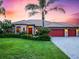 Inviting single-story home features a manicured lawn, mature palms, three-car garage, and a welcoming entryway at 312 148Th Ne Ct, Bradenton, FL 34212