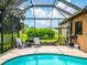 Screened in pool area with lounge chairs and an umbrella-covered table overlooking the yard and pond at 312 148Th Ne Ct, Bradenton, FL 34212