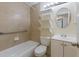 Cozy bathroom featuring a tub, toilet, vanity, and tiled walls, complemented by shelving and a framed mirror at 3253 Beneva Rd # 103, Sarasota, FL 34232