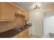 Efficient kitchen featuring wood cabinetry, stainless steel sink, tile backsplash, and black countertops at 3253 Beneva Rd # 103, Sarasota, FL 34232