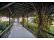 A covered walkway adorned with lush greenery leads to residences, creating a tranquil path at 3253 Beneva Rd # 103, Sarasota, FL 34232