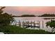 Picturesque waterfront scene featuring a private dock with boat lift, calm waters, and lush green vegetation under a dramatic sunset at 3799 Flamingo Ave, Sarasota, FL 34242
