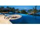 Aerial view of a custom fire pit surrounded by an infinity pool and lush tropical landscaping with bay and trees at 3799 Flamingo Ave, Sarasota, FL 34242