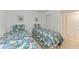 Well-lit bedroom with twin beds, bright linens, and minimalist decor against white walls at 3801 Lake Bayshore Dr # H413, Bradenton, FL 34205