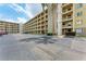 Condominium exterior featuring multiple floors, balconies, and a spacious parking lot with mature landscaping at 3801 Lake Bayshore Dr # H413, Bradenton, FL 34205