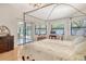 Bright main bedroom with four poster bed, wood floors, chandelier and sliding glass door access to lanai at 4137 Woodview Dr, Sarasota, FL 34232