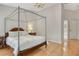Spacious main bedroom with wood floors, four poster bed, chandelier and ensuite bathroom at 4137 Woodview Dr, Sarasota, FL 34232