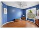 Blue bedroom with a ceiling fan, hardwood floors, a cushioned storage bench, and a side table with a lamp at 4222 Lanai Dr, Sarasota, FL 34241