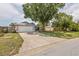 View of a single-story home featuring an attached two-car garage, front yard with mature trees, and partial lawn at 4222 Lanai Dr, Sarasota, FL 34241