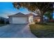 Evening view of a well-lit, inviting home with a manicured lawn, two-car garage, and lovely front yard landscaping at 4222 Lanai Dr, Sarasota, FL 34241