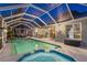 Night shot of the screened-in pool and spa with outdoor entertaining area and stylish wall lighting at 4222 Lanai Dr, Sarasota, FL 34241