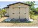 Exterior view of the backyard shed with double doors and adjacent landscaping at 435 Whispering Oaks Ct, Sarasota, FL 34232