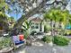 Charming cottage exterior featuring mature trees, lush tropical landscaping and inviting outdoor seating area at 4412 125Th W St, Cortez, FL 34215