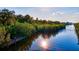 A serene waterfront view of a dock extending into the water surrounded by lush green vegetation and sunny skies at 4603 4Th E Ave, Bradenton, FL 34208