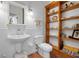 Cozy bathroom featuring a pedestal sink, tiled walls, and a rustic wooden shelving unit for storage at 512 77Th St, Holmes Beach, FL 34217