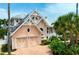 Charming two-story home featuring a brick driveway, multiple garage doors, and lush landscaping with palm trees at 512 77Th St, Holmes Beach, FL 34217
