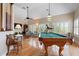 Spacious game room featuring a pool table, hardwood floors, plantation shutters, and comfortable seating at 512 77Th St, Holmes Beach, FL 34217