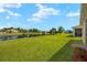 Large backyard with a serene pond view, complemented by lush green grass and mature trees at 5358 Shell Mound Cir, Punta Gorda, FL 33982