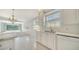 Modern kitchen with tile flooring, white cabinets and stainless steel appliances with a view of the living room at 5566 Avellino Pl, Sarasota, FL 34238