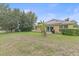 Spacious backyard with lush lawn, mature trees, and the home's exterior with solar panels at 5618 Sheer Bliss Loop, Land O Lakes, FL 34639