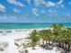 Beautiful white sand beach with palm trees and clear blue ocean water at 6512 Midnight Pass Rd # 301, Sarasota, FL 34242