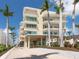 Stunning exterior of the elevated beachfront building with palm trees and tropical landscaping at 6512 Midnight Pass Rd # 301, Sarasota, FL 34242
