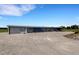 Extensive horse barn with multiple stalls and a spacious gravel parking area, set in a rural landscape at 7160 Myakka Valley Trl, Sarasota, FL 34241
