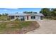 Home exterior displaying metal roof, vibrant orange door, and tidy lawn at 7160 Myakka Valley Trl, Sarasota, FL 34241