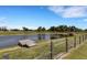 Picturesque pond with a small wooden dock, surrounded by lush greenery and a wire fence at 7160 Myakka Valley Trl, Sarasota, FL 34241