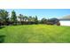 Large backyard with lush green grass, mature landscaping, trees, and a screened lanai at 8077 Sandstar Way, Sarasota, FL 34240