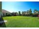 Expansive backyard showcases lush green lawn, mature trees, and a screened lanai at 8077 Sandstar Way, Sarasota, FL 34240