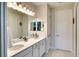 Bright bathroom features double sinks with modern fixtures and a large mirror with decorative lighting at 8077 Sandstar Way, Sarasota, FL 34240