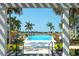 Palm trees and lush greenery surround the community pool with lake views at 8077 Sandstar Way, Sarasota, FL 34240