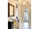Bright foyer with a decorative mirror, modern dresser, and tile flooring leading to the living area at 8077 Sandstar Way, Sarasota, FL 34240