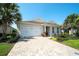 Inviting single-story home with a paver driveway, two-car garage, and colorful tropical landscaping at 8077 Sandstar Way, Sarasota, FL 34240