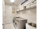 Functional laundry room with modern washer and dryer, storage shelf, and ample counter space at 8077 Sandstar Way, Sarasota, FL 34240