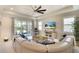 Bright living room with a ceiling fan, large sofa, neutral decor, and sliding glass doors to the patio at 8077 Sandstar Way, Sarasota, FL 34240