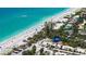 Aerial view of a beach with white sand, clear blue water, beachgoers, and palm tree lined street at 8897 Midnight Pass Rd # 407, Sarasota, FL 34242