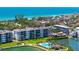 Aerial view of condo complex with community pool, lush landscaping, and marina near the ocean at 8897 Midnight Pass Rd # 407, Sarasota, FL 34242