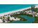 Aerial view of a pristine beach, with calm turquoise waters, lush greenery, and a boat launch area at 8897 Midnight Pass Rd # 407, Sarasota, FL 34242