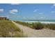 Picturesque beach view with soft sand, clear turquoise water, and lush dune vegetation at 8897 Midnight Pass Rd # 407, Sarasota, FL 34242