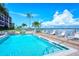 Community pool with lounge chairs overlooking the bay on a beautiful sunny day with palm trees at 8897 Midnight Pass Rd # 407, Sarasota, FL 34242