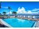 Community pool overlooking the bay with lounge chairs and many palm trees on a beautiful sunny day at 8897 Midnight Pass Rd # 407, Sarasota, FL 34242