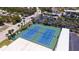Aerial view of community tennis courts with vibrant blue surfaces and palm trees on a beautiful day at 8897 Midnight Pass Rd # 407, Sarasota, FL 34242