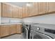 Spacious laundry room with wooden cabinets, white countertops, and modern washer and dryer at 8982 Baroque Ter, Sarasota, FL 34240