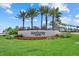 Community entrance sign surrounded by vibrant flowers, lush greenery, and mature palm trees at 8982 Baroque Ter, Sarasota, FL 34240
